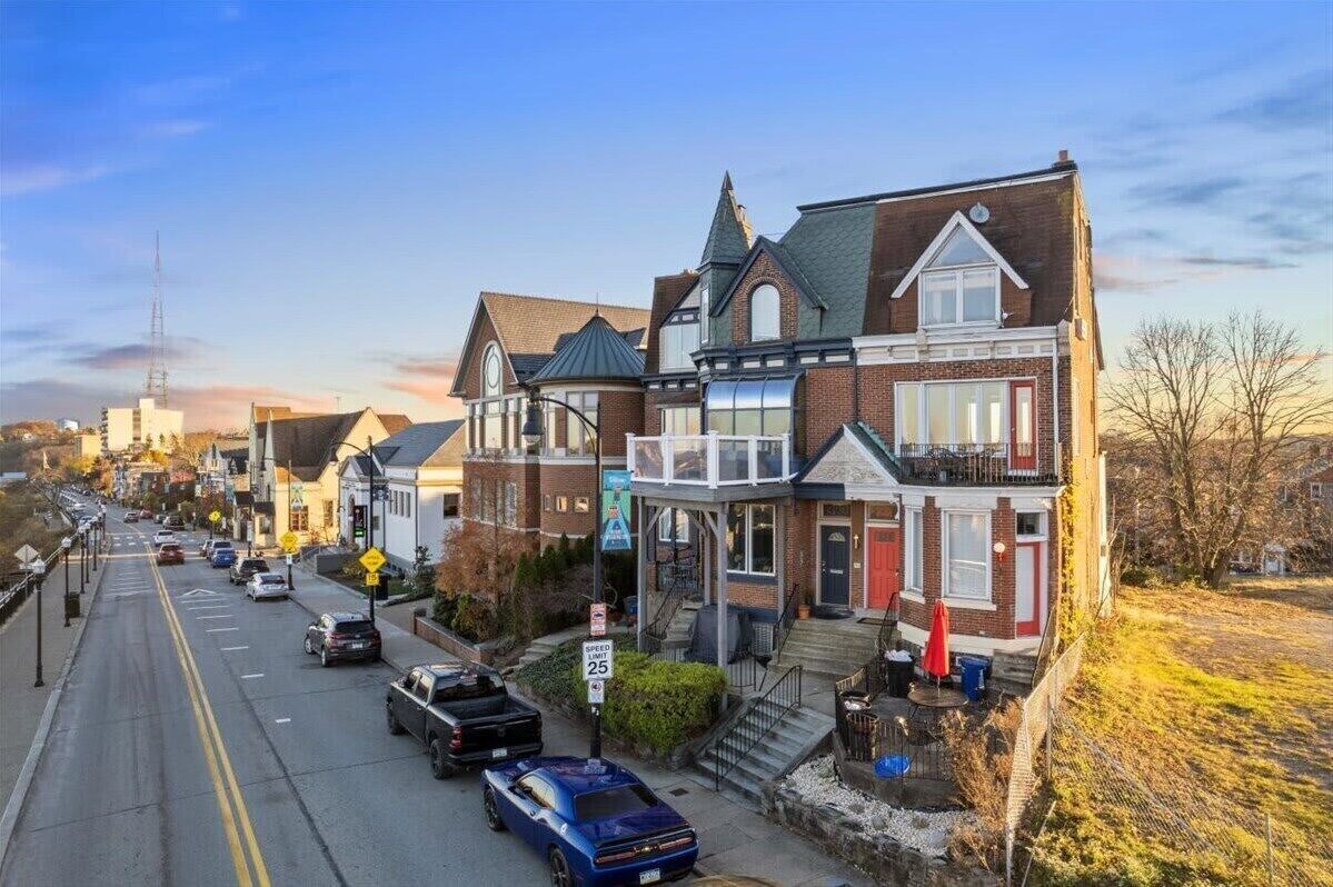 A street view of a residential area with houses, a clear sky, and a speed limit sign of 25 mph.