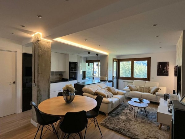 Relax in this stylish living space with a central dining table, comfortable sofa, and large window offering a view.