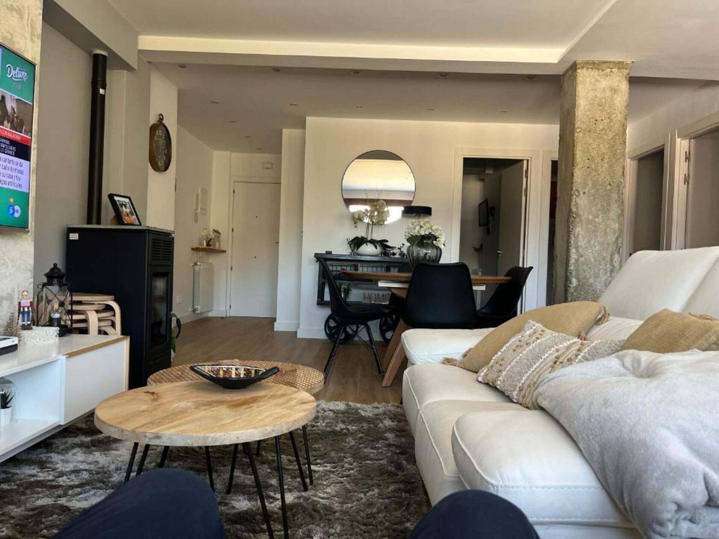 A modern living room with a white sofa, a wooden coffee table, and a dining area with a round table and chairs.
