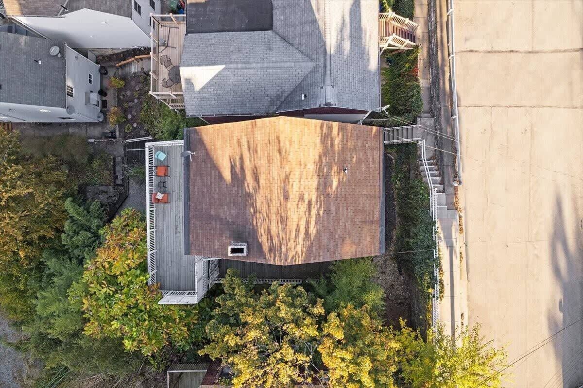 An aerial view of a residential area with a large, flat-roofed building surrounded by trees and other houses.