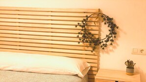 A bedroom with a wooden slat headboard, a bed with a patterned bedspread, a bedside table with a plant, and a nightstand with a drawer. - Cozy 2BR Apartment with Pool in Jaca – Sleeps 6, 2 Bathrooms (Jaca)