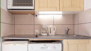 Une cuisine compacte équipée d’un four à micro-ondes, d’une machine à café et d’un évier.
