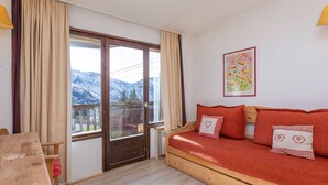 Une pièce chaleureuse avec un canapé en bois, une table en bois et une vue sur les montagnes par une grande fenêtre.