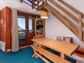 A wooden interior with a table and benches, a television, and a view of the outdoors.