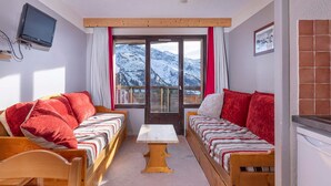 Une pièce chaleureuse avec deux lits en bois, une petite table et une fenêtre donnant sur la montagne.