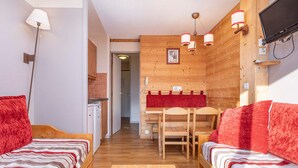 Une pièce chaleureuse avec deux lits en bois, une table à manger et un coin cuisine.