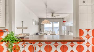 A kitchen with a wooden countertop, a sink, and a view of a balcony with a chair and a table.
