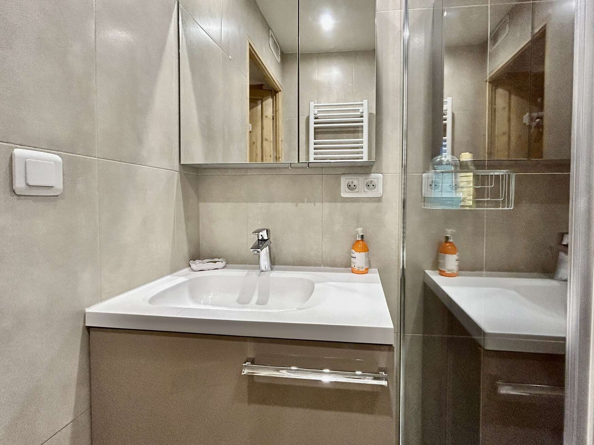 Ein modernes Badezimmer mit einem großen Waschbecken, einem Spiegel und einer Duschkabine aus Glas.