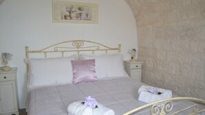 A bed with a headboard, two bedside tables, and a wall-mounted picture. - Trulli of the Chain (Martina Franca)