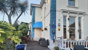 A building with a blue and white facade, a signboard for Garway Lodge, outdoor seating, and potted plants.
