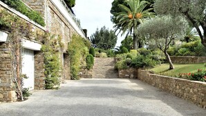 A stone building with a gravel driveway leading to a gated entrance.