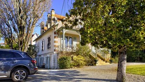 Una casa con entrada de coches, un coche estacionado y un árbol.