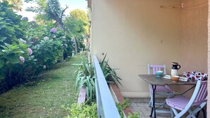 Un patio con mesa y sillas, rodeado de vegetación y un cielo despejado.