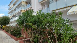 A multi-story residential building with balconies, a brick pathway, and various plants. - 2-Bedroom Apartment in Blanes with Pool, Near Beach (Blanes)
