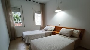 A room with two single beds, a wooden headboard, a small bedside table, and a window with curtains. - 2-Bedroom Apartment in Blanes with Pool, Near Beach (Blanes)