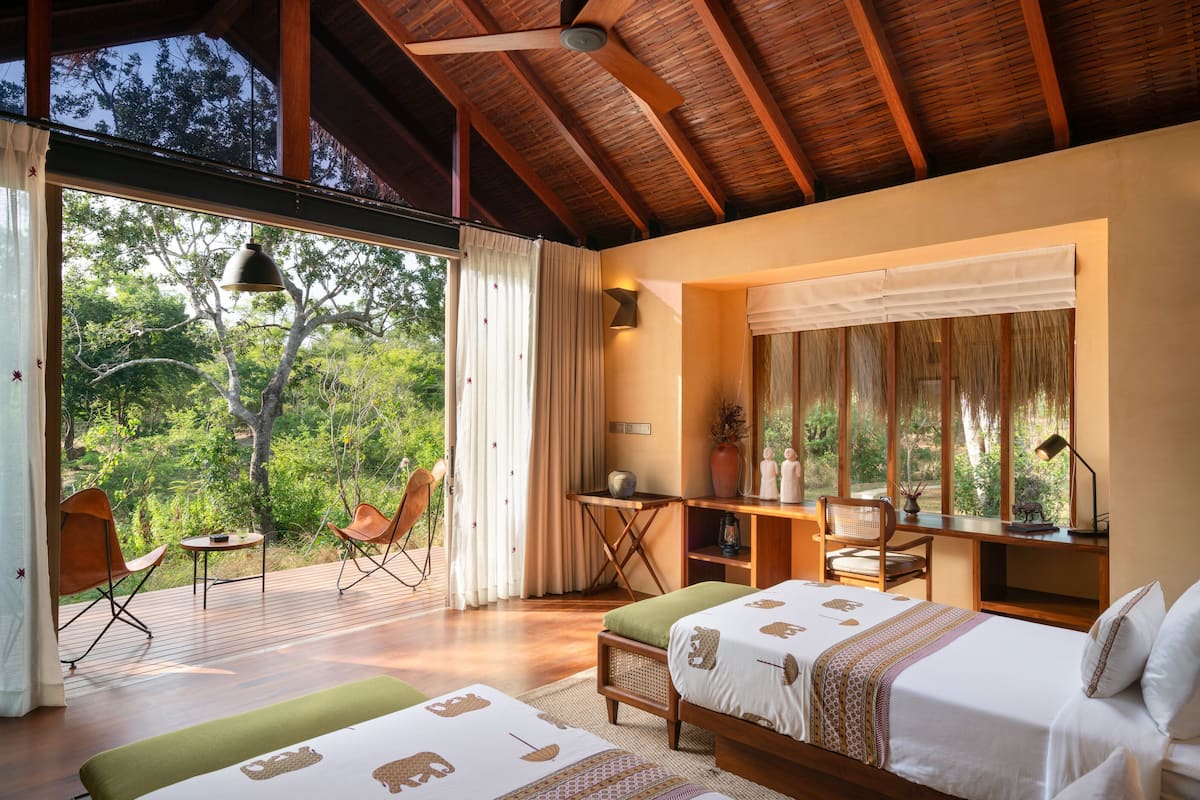 A spacious room with a large window, a wooden ceiling, a desk, and a bed.