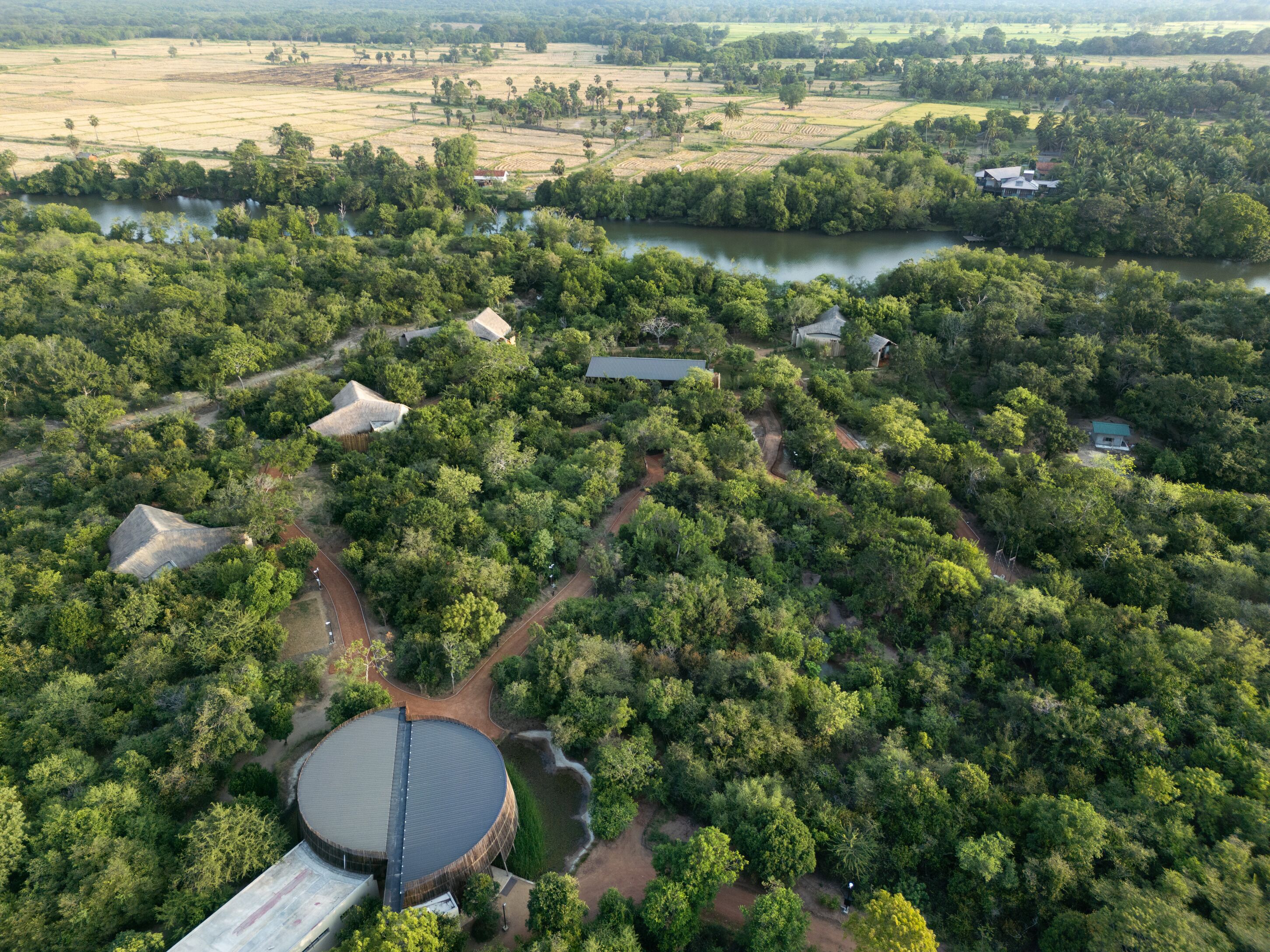 Vista aérea de una zona rural con casas dispersas, un río y abundante vegetación.