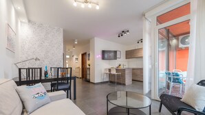 Un salon moderne avec un canapé, une table basse en verre et un coin repas comprenant des chaises et une table.