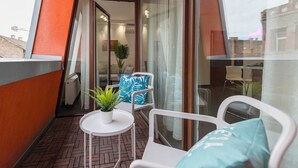 Un balcon avec une table blanche, deux chaises et un pot de fleurs.
