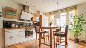 Una cocina moderna con armarios blancos, horno empotrado y comedor con sillas y mesa de madera.