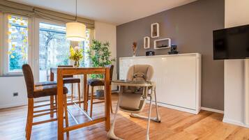 Ein modernes Wohnzimmer mit Essbereich, Hochstuhl und Fernseher an der Wand.