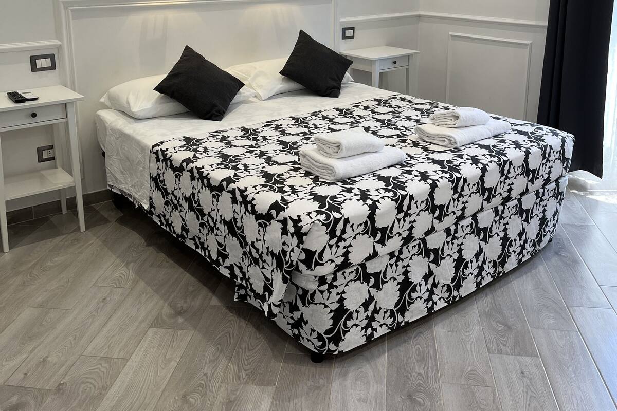 A neatly arranged bedroom with a bed, bedside tables, and a wall-mounted air conditioner.