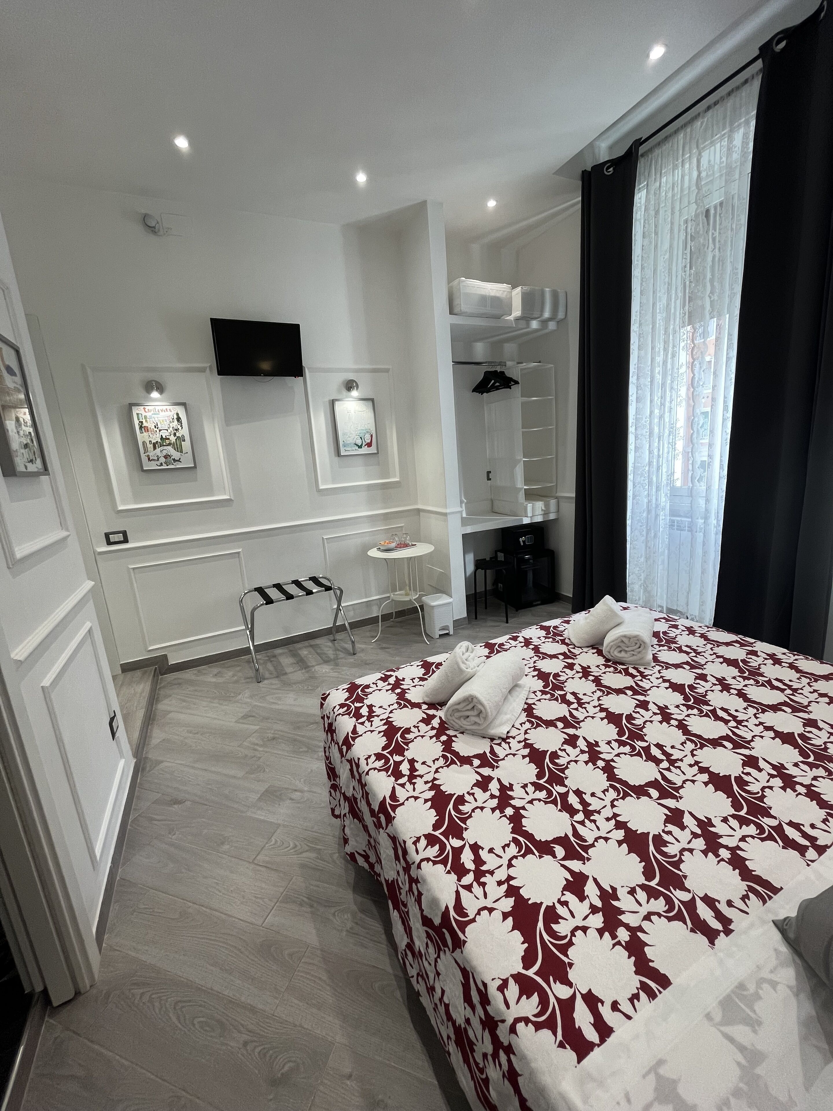 Une chambre d’hôtel avec un grand lit, un bureau, une chaise, une petite table, un miroir et un téléviseur fixé au mur.