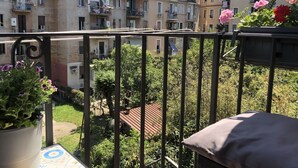 A balcony with a view of multi-story buildings, a garden area, and a red-roofed structure. - Domus Giordano (Rome)