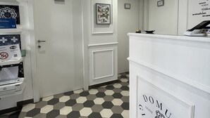 A hotel reception area with a hexagonal patterned floor, a reception desk, and a wall-mounted air conditioning unit. - Domus Giordano (Rome)