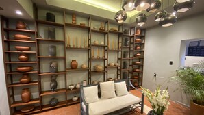 A living room with a sofa, shelves with pottery, and a vase with flowers. - Lofts Marques Oaxaca (Oaxaca)