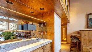 A wooden interior with a kitchen area featuring a large island, wooden cabinets, and a bar area with stools.
