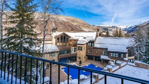 A snow-covered resort with a pool, mountain views, and a large building with multiple windows.