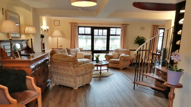A spacious living room with a fireplace, multiple seating options, and a staircase leading to an upper level.