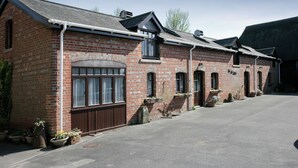 A brick building with a large window and a door, potted plants, and a clear sky.
