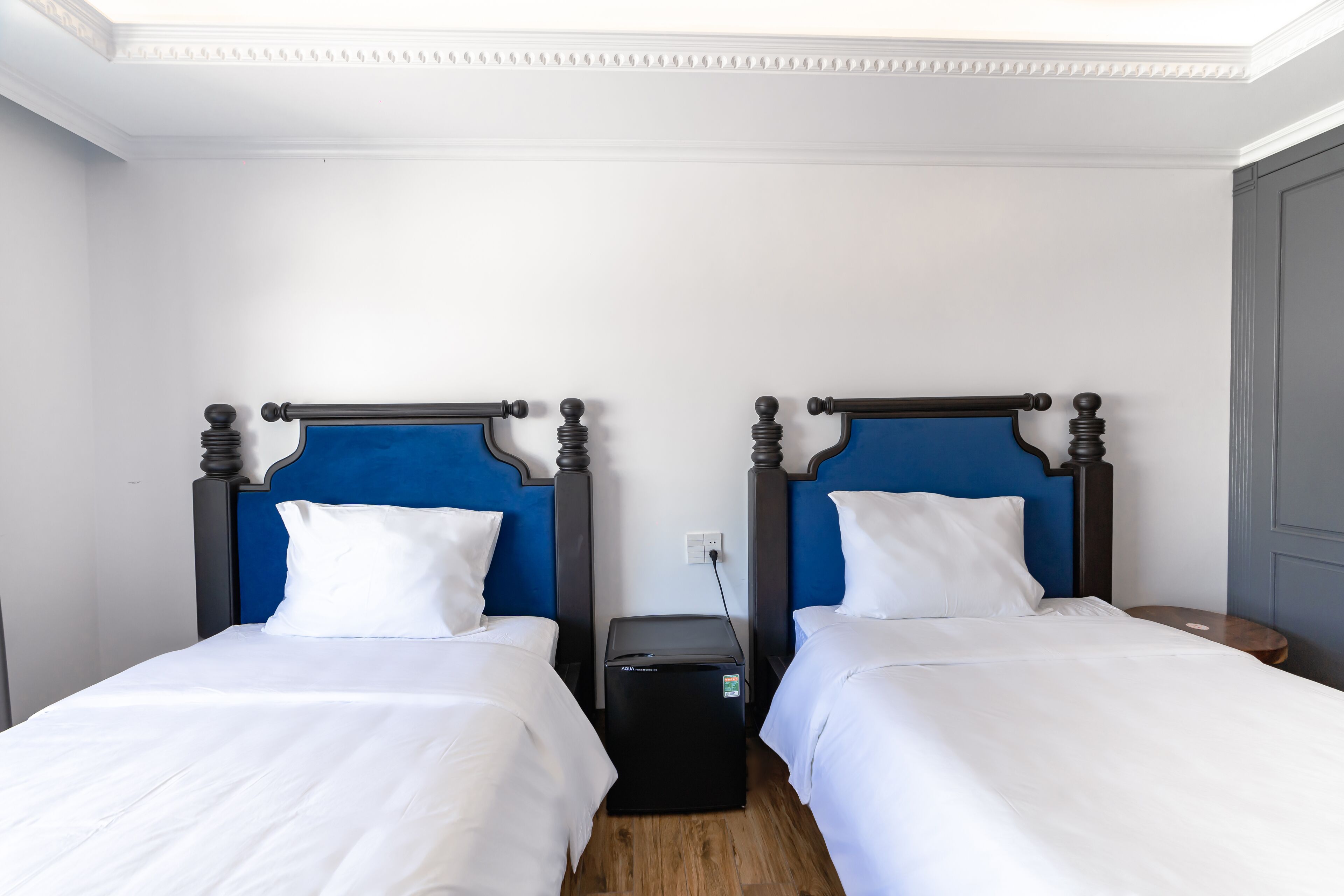 A hotel room with two single beds, each with a wooden headboard and white bedding.