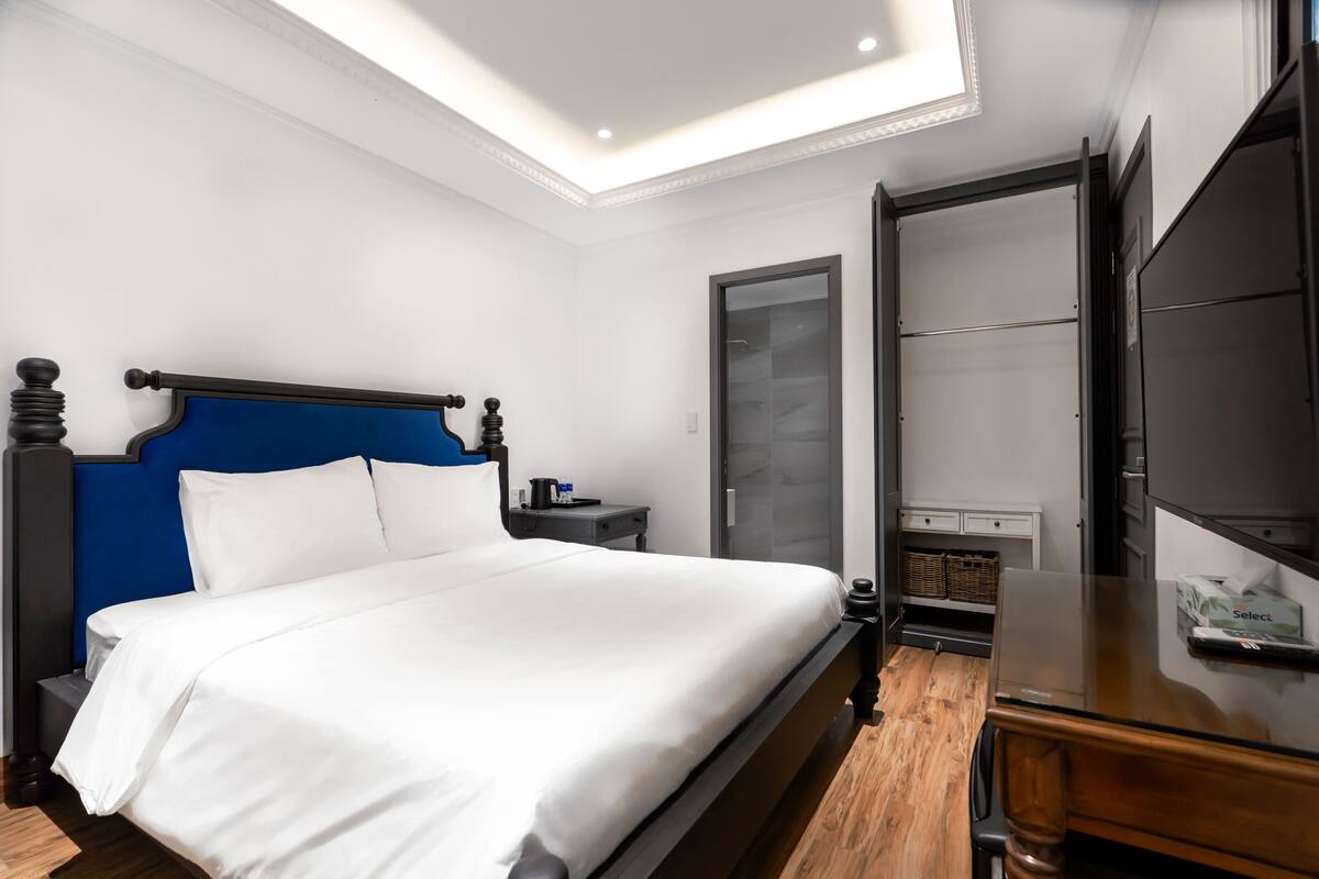 A neatly made bed with white linens, a wooden headboard, and a small bedside table with a lamp.