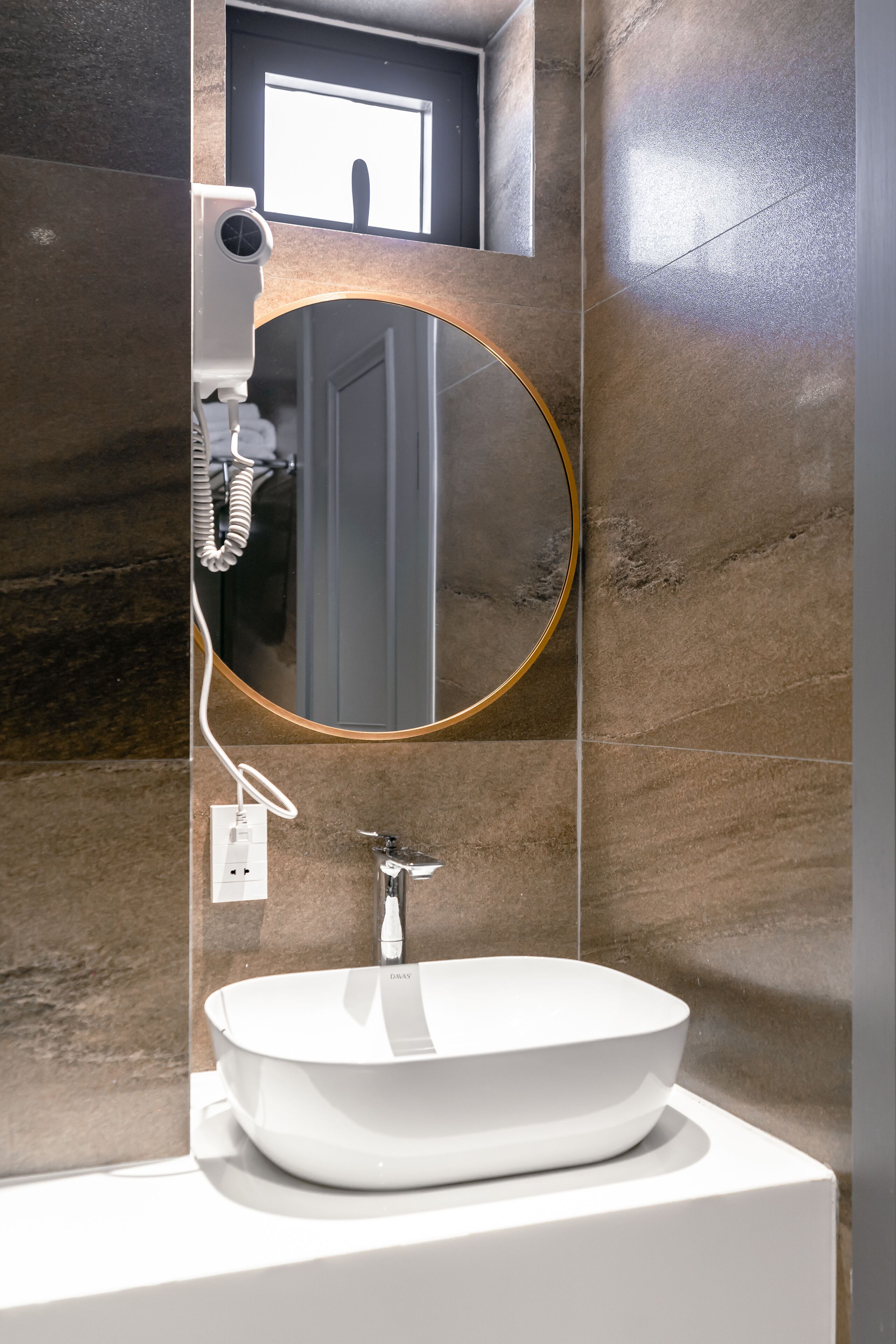 A bathroom with a round mirror, a white sink, and a towel rack.