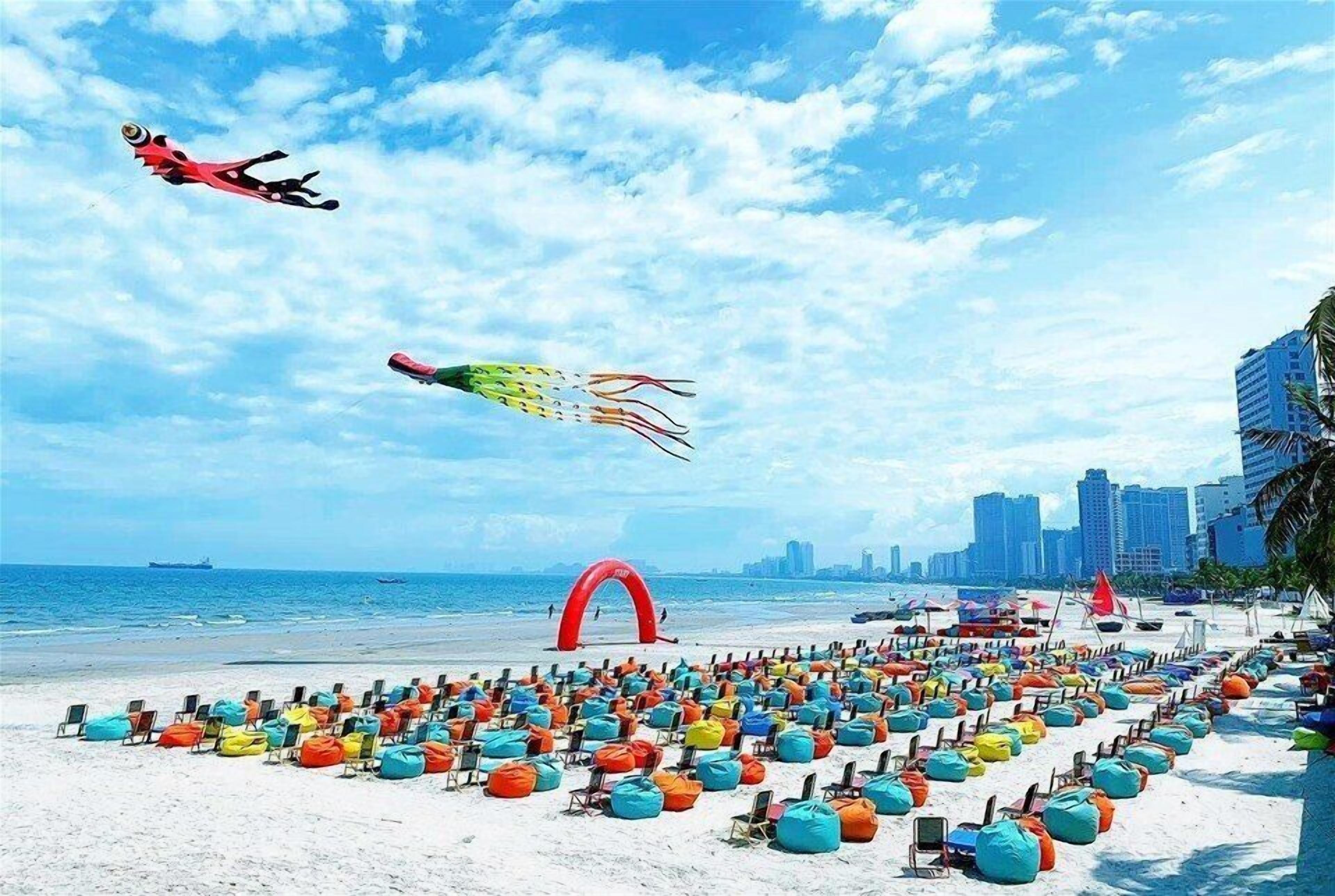 A beach with colorful bean bag chairs and a red arch structure.