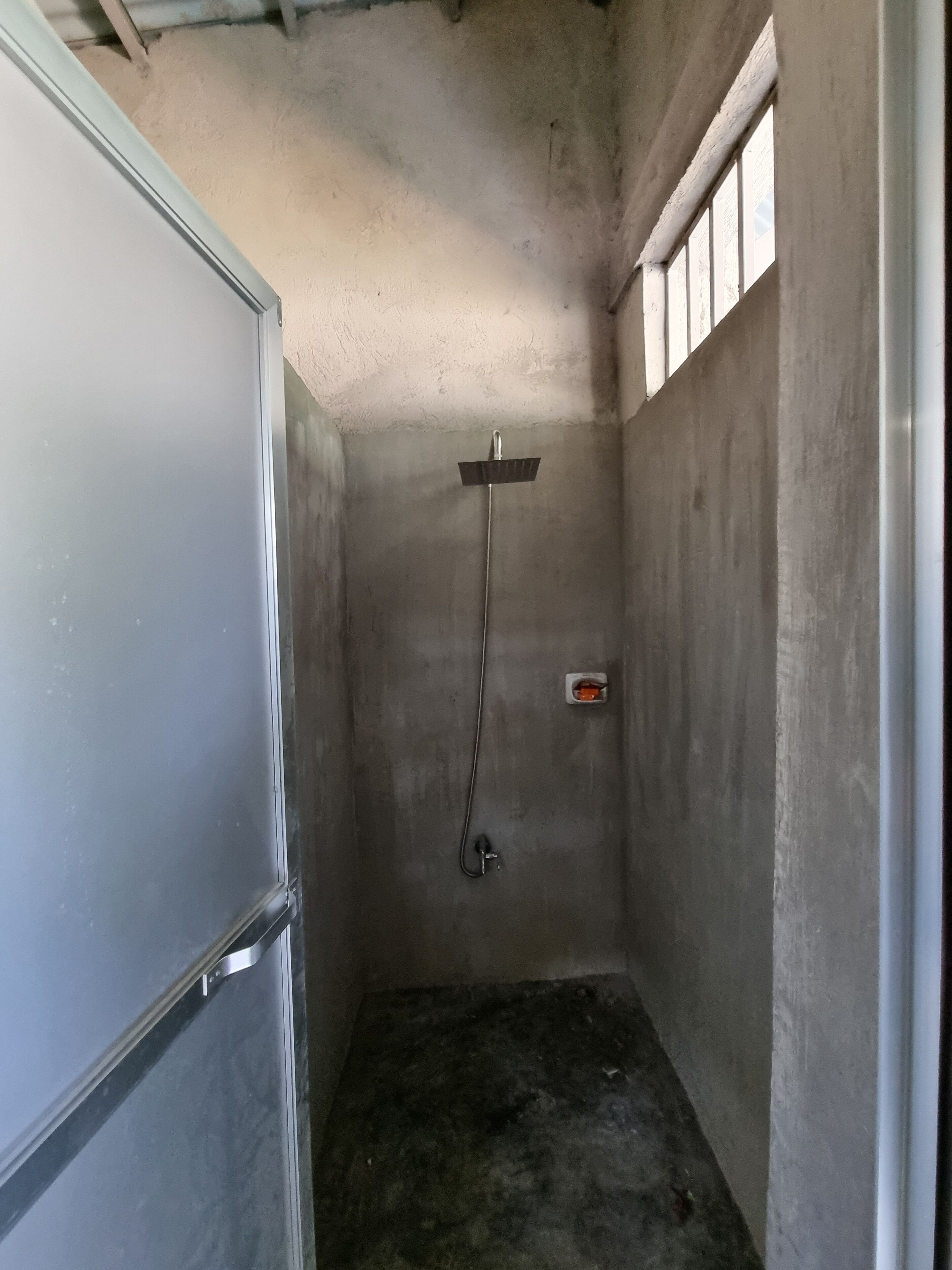 Une petite cabine de douche fermée, équipée d’un pommeau de douche et d’un panneau de commande.