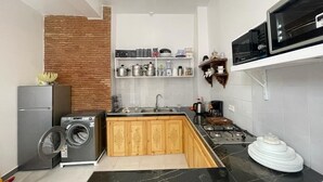 Een kleine keuken met een wasmachine, een magnetron en een fornuis.