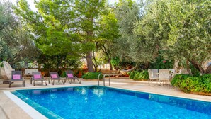 A swimming pool with lounge chairs and a wooden deck. - Villa Olivia is on the corner of one of the prettiest streets in Kalkan (kas)