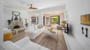 A spacious living room with white furniture, a stone fireplace, and a view to the outside. - Villa Olivia is on the corner of one of the prettiest streets in Kalkan (kas)