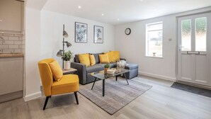 Ein modernes Wohnzimmer mit einer Couch, einem Sessel, einem Couchtisch und einem Essbereich mit Küchenzeile.