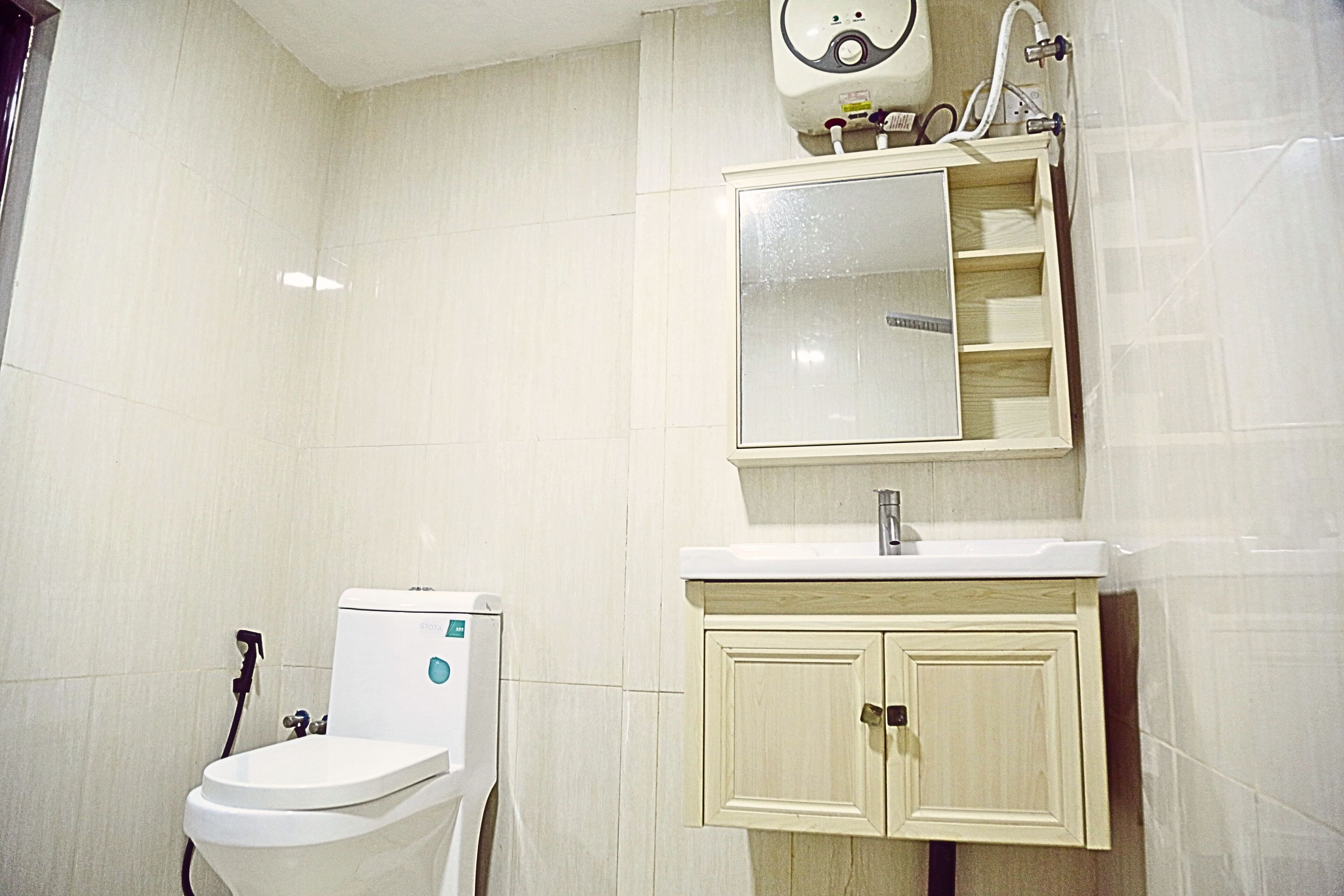 A bathroom with a toilet, sink, mirror, and cabinet.