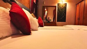 A hotel room with a bed, pillows, a nightstand, a mirror, and a painting on the wall. - Ared Villa (Seeduwa - Katunayake)