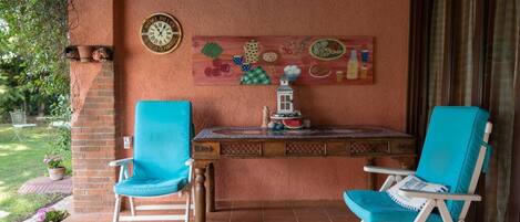 Un patio con dos sillas turquesas, una mesita y un reloj de pared.