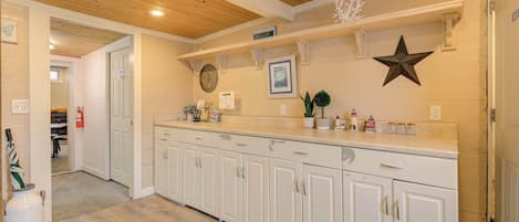 A kitchen with white cabinets, a wooden ceiling, and a countertop with various items.
