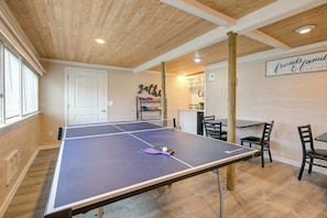Una mesa de ping pong con sillas, techo de madera y un letrero que dice 'friends family & gather'.