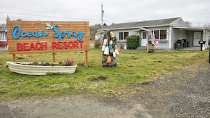 A wooden sign for Ocean Spring Beach Resort with a small boat and a figure in a beach outfit.