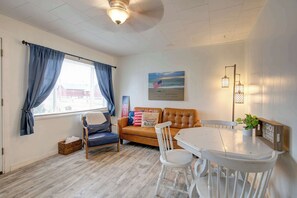 A room with a window, a sofa, a dining table, and a lamp.